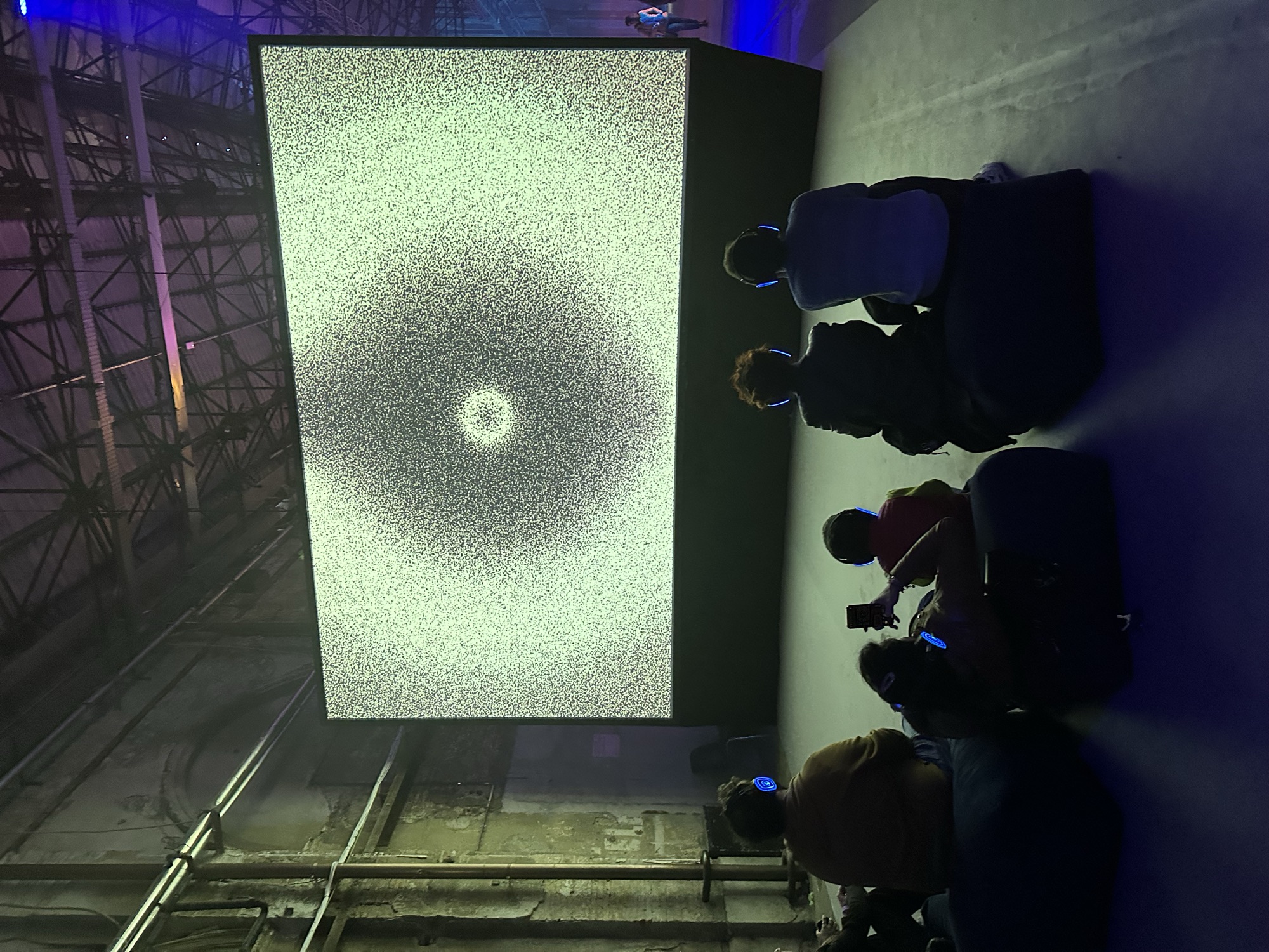Inner Quadrant — audience with headphones watching a generative particle ring on the large screen