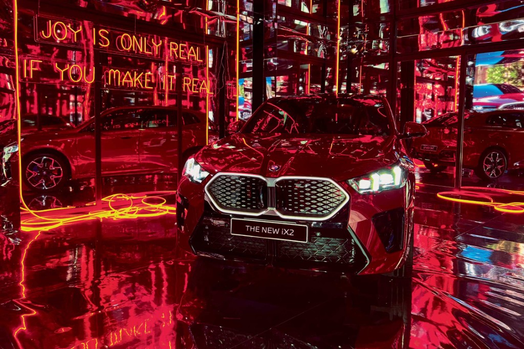 Make it Real — the new BMW iX2 in a mirrored room of red neon: Joy is only real if you make it real