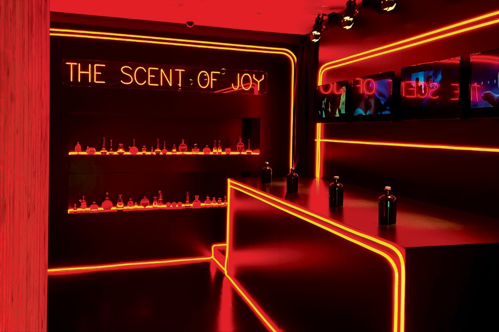 Make it Real — The Scent of Joy: perfume bottles on lit shelves in a red neon room