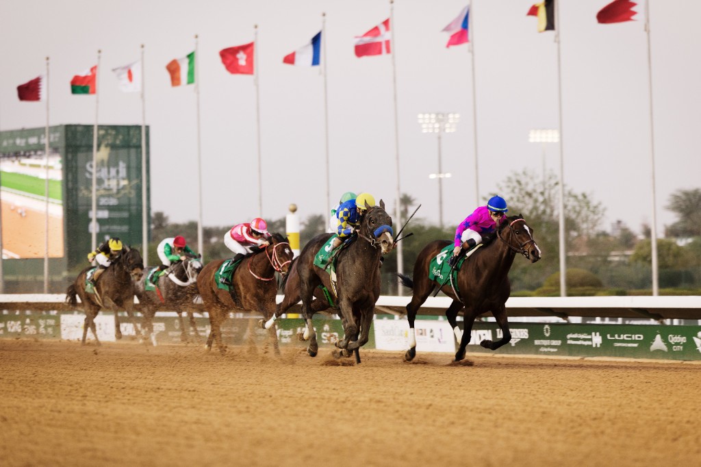 Saudi Cup — horses and jockeys racing on the dirt track beneath international flags